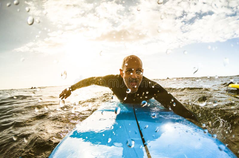 Individuo de la persona que practica surf que se bate con la tabla hawaiana en la puesta del sol en Tenerife