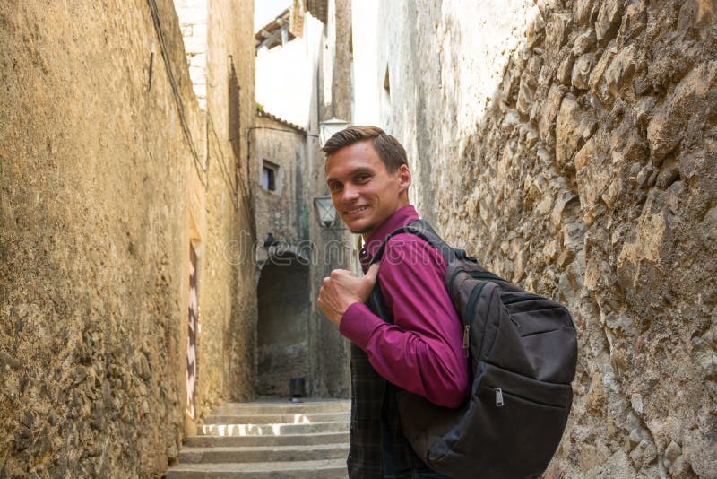 Individuo hermoso joven con una mochila que sonríe, caminando a lo largo del fotografía de archivo libre de regalías Individuo hermoso joven con una mochila que sonríe, caminando a lo largo del fotografía de archivo libre de regalías
