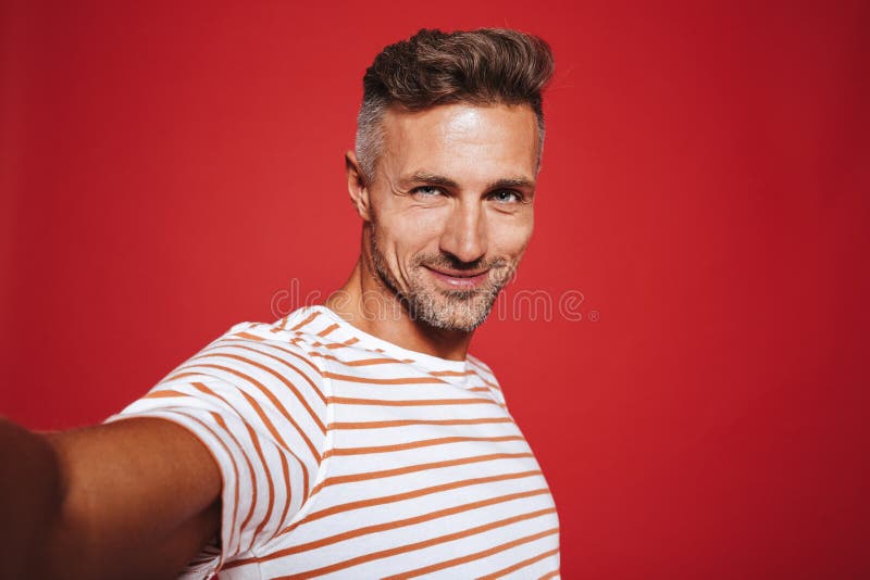 Individuo hermoso 30s en la camiseta rayada que sonríe mientras que toma el selfie imagen de archivo Individuo hermoso 30s en la camiseta rayada que sonríe mientras que toma el selfie imagen de archivo