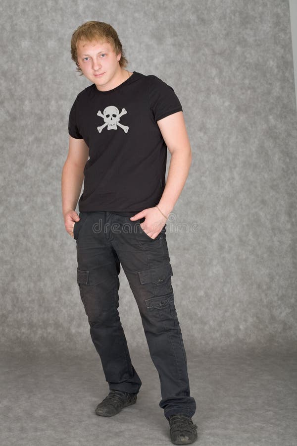The young guy in a T-shirt with piracy symbolics on gray. The young guy in a T-shirt with piracy symbolics on gray