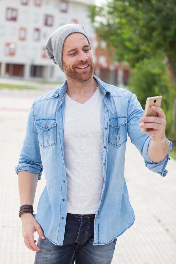 Indivíduo ocasional da forma que toma uma caminhada com seu móbil imagens de stock Indivíduo ocasional da forma que toma uma caminhada com seu móbil imagens de stock
