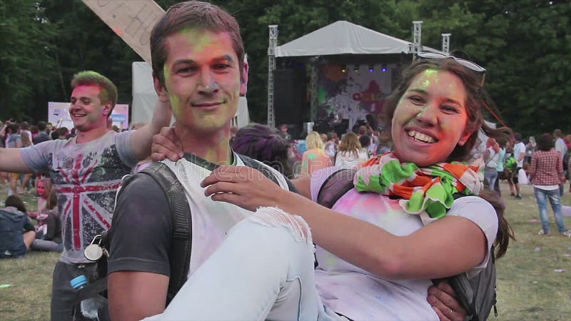 Indivíduo que guarda a amiga nos braços, aperto dos jovens, enganando ao redor no festival