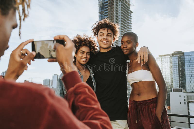 Indivíduo que toma uma foto de seus amigos em um telhado foto de stock royalty free Indivíduo que toma uma foto de seus amigos em um telhado foto de stock royalty free
