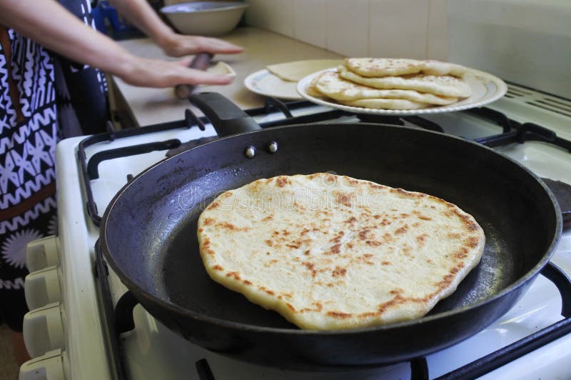 Indo-Fijian woman cooking homemade Naan bread in the kitchen. Indian food. Indo-Fijian woman cooking homemade Naan bread in the kitchen. Indian food.