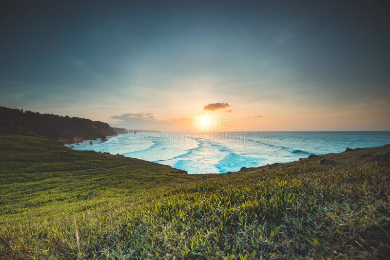 Indonesia ocean sunrise, green cliff beach nobody nature landscape with greenery grass at clear sky in summer, Wild Sumba Island, Asia. Majestic Indonesian National Park on rock shore of Indian Gulf