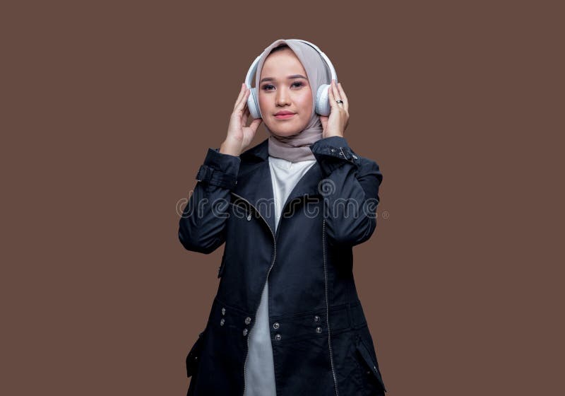 Indonesisk kvinna i hijab som använder sig av trådlösa hörlurar arkivfoto