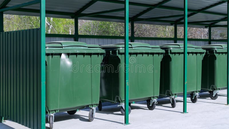 Indoor garbage collection area with green trash containers in the city. stock photos