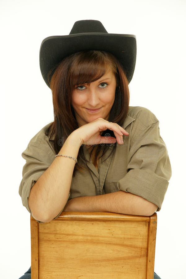 Indoor portrait of beautiful young woman cowgirl in hat, sitting on the chair