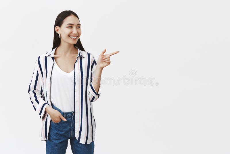 Indoor shot of attractive beautiful european female employee pointing and looking right with broad satisfied smile