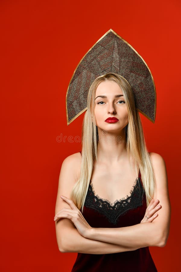 Indoor shot of serious strict young female dressed velvet dress keeping arms folded stock photo Indoor shot of serious strict young female dressed velvet dress keeping arms folded stock photo