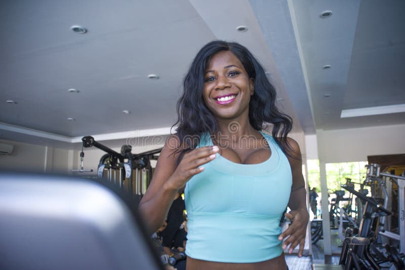 Indoors gym portrait of young attractive and happy black african American sporty woman training treadmill running workout at fitne royalty free stock image Indoors gym portrait of young attractive and happy black african American sporty woman training treadmill running workout at fitne royalty free stock image