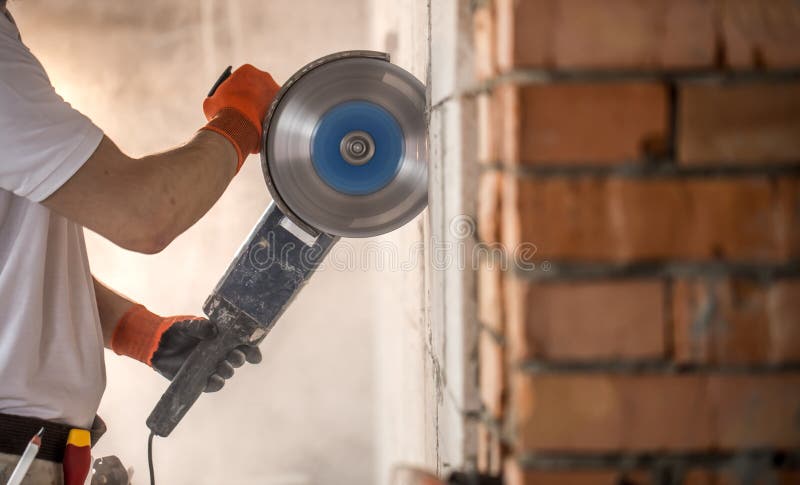 The industrial Builder works with a professional angle grinder to cut bricks and build interior walls. Electrician stock photos The industrial Builder works with a professional angle grinder to cut bricks and build interior walls. Electrician stock photos