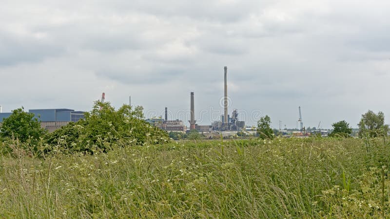Nature and industry - industrial buildings in the port of antwerp sean from the green border on the other side of river Scheldt. Industrial buildings, chimneys royalty free stock photos Nature and industry - industrial buildings in the port of antwerp sean from the green border on the other side of river Scheldt. Industrial buildings, chimneys royalty free stock photos