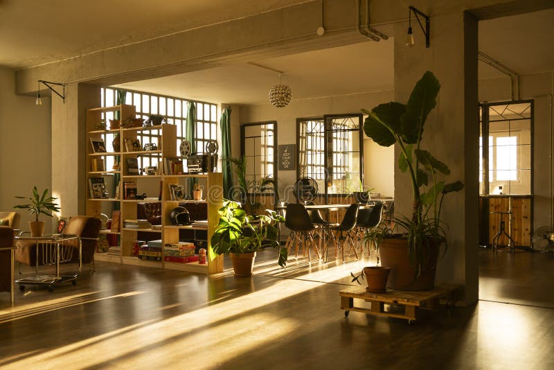 Industrial design loft, with large windows and coworking-office area. Dawn light. Interior design. Living room at home.