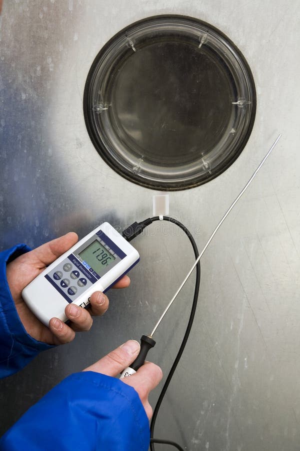 Man holding digital thermometer in front of ventilation unit. Man holding digital thermometer in front of ventilation unit.