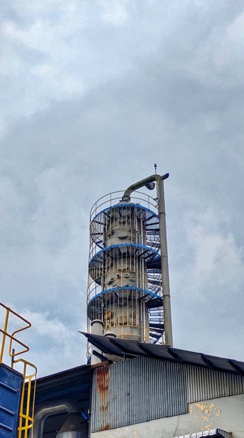Industrial distillation column or chemical processing tower at a factory under a cloudy sky. royalty free stock photo