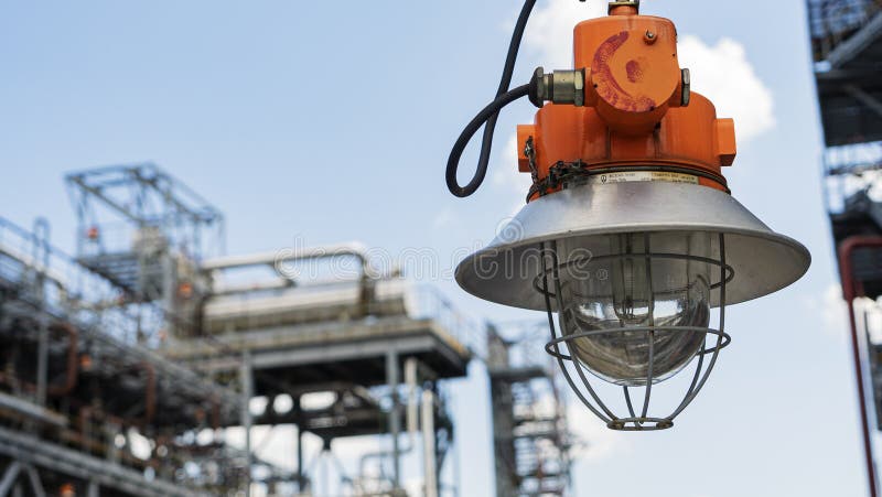 Industrial explosion proof lantern on the background of the refinery plant and classic blue sky. Space for text