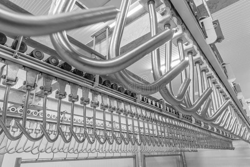 Industrial loading dock area inside cold storage warehouse. Meat hanging hooks hanging on the rail system stock images