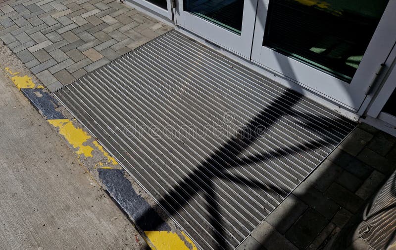 industrial mat cleaning zones at the entrance to the building. black plastic-metal mat in the shape of an arch or half-circle lies on the limestone mosaic tiles
