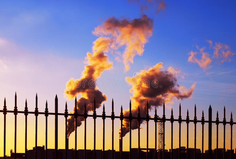 Industrial smoking pipes at sunset