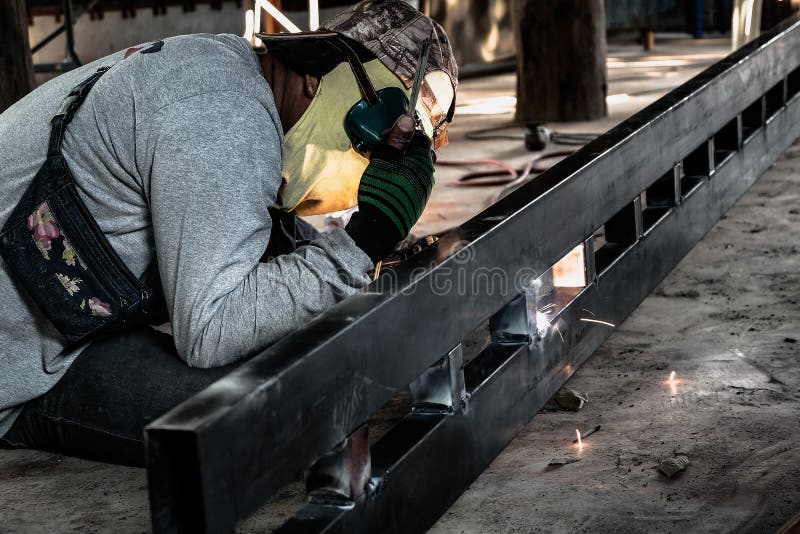 Industriearbeiter an der Fabrikschwei?ensnahaufnahme Elektrisches Rad, das auf Stahlkonstruktion in der Fabrik reibt stockfoto Industriearbeiter an der Fabrikschwei?ensnahaufnahme Elektrisches Rad, das auf Stahlkonstruktion in der Fabrik reibt stockfoto