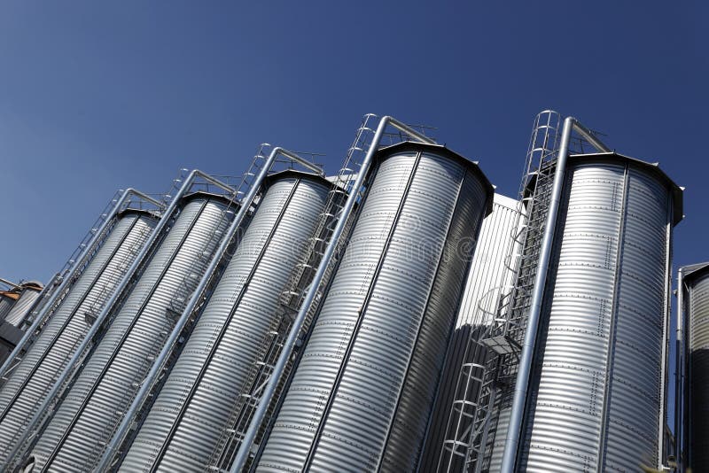 Large industrial storage silos or tanks against a blue sky. Large industrial storage silos or tanks against a blue sky.