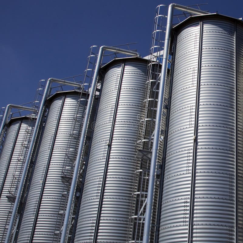 Large, industrial storage silos or vertical tanks. Blue sky background. Large, industrial storage silos or vertical tanks. Blue sky background