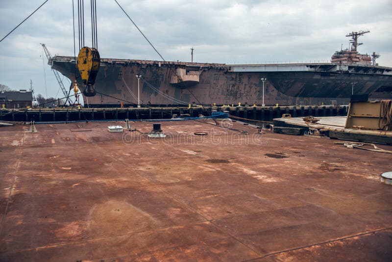 Industrieller Hintergrund der rostigen Metallplattform im Dockhafen mit Schlachtschiff stockfotografie Industrieller Hintergrund der rostigen Metallplattform im Dockhafen mit Schlachtschiff stockfotografie