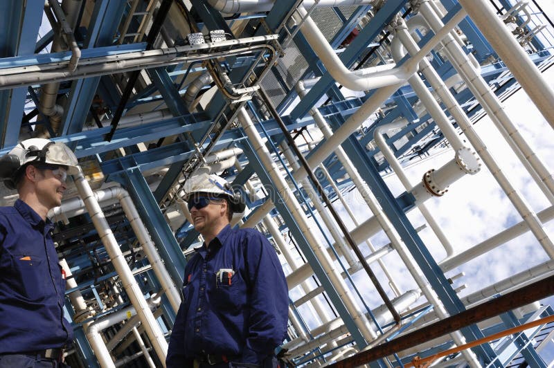 Two industry workers in the oil and gas industry, giant pipeline construction in background. Two industry workers in the oil and gas industry, giant pipeline construction in background