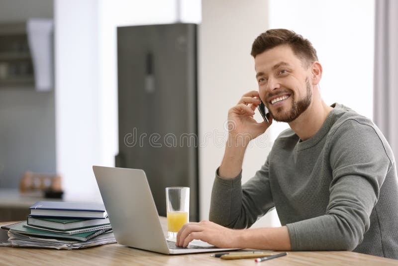 Indépendant parlant au téléphone tandis qu'utilisant l'ordinateur portable à la maison photo libre de droits Indépendant parlant au téléphone tandis qu'utilisant l'ordinateur portable à la maison photo libre de droits