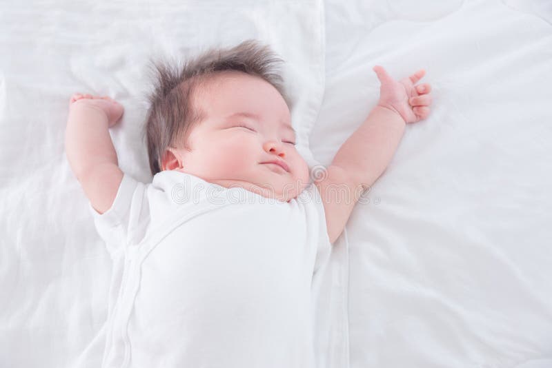 Infant stretching on white bed in the morning