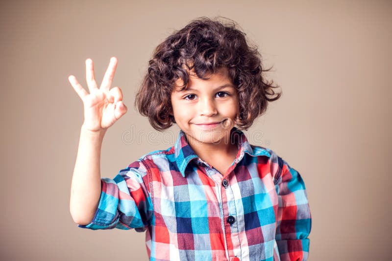 Infanzia, moda, pubblicità e ideologia delle persone - un ragazzo felice che mostra il segno della mano fotografia stock Infanzia, moda, pubblicità e ideologia delle persone - un ragazzo felice che mostra il segno della mano fotografia stock