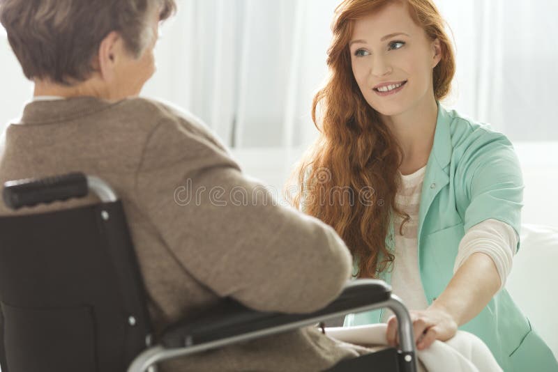 Supportive young nurse looking at elder woman. Supportive young nurse looking at elder woman