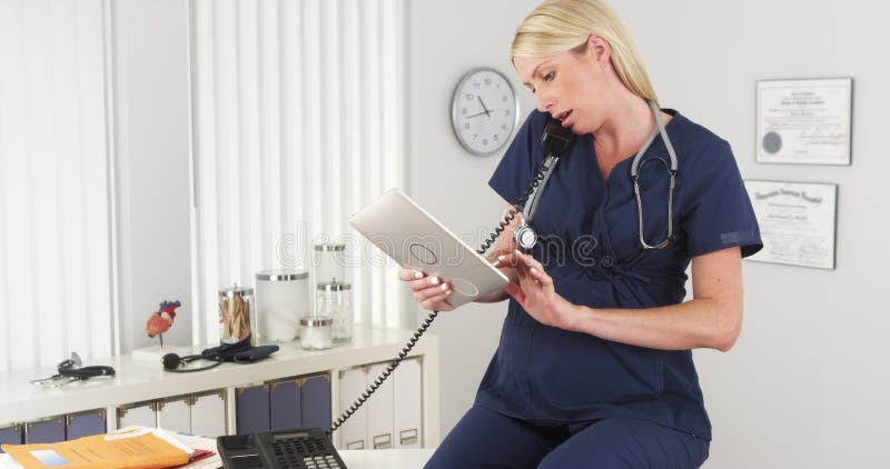 Infermiere incinto che lavora nell'ufficio immagini stock libere da diritti Infermiere incinto che lavora nell'ufficio immagini stock libere da diritti