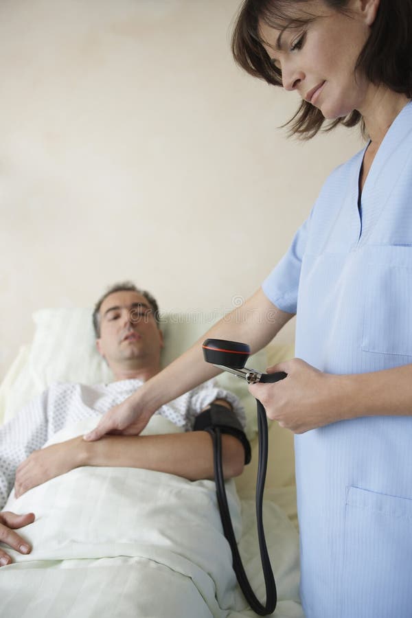 Infermiere Taking Blood Pressure ed impulso del paziente fotografia stock Infermiere Taking Blood Pressure ed impulso del paziente fotografia stock
