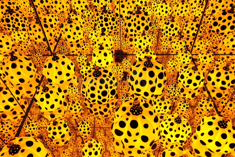 An infinity mirror room full with yellow and black polka dots pumpkins installation art by Japanese artist, Kusama Yayoi