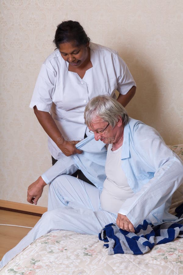 Infirmière aidant l'homme plus âgé obtenant habillé photo libre de droits Infirmière aidant l'homme plus âgé obtenant habillé photo libre de droits