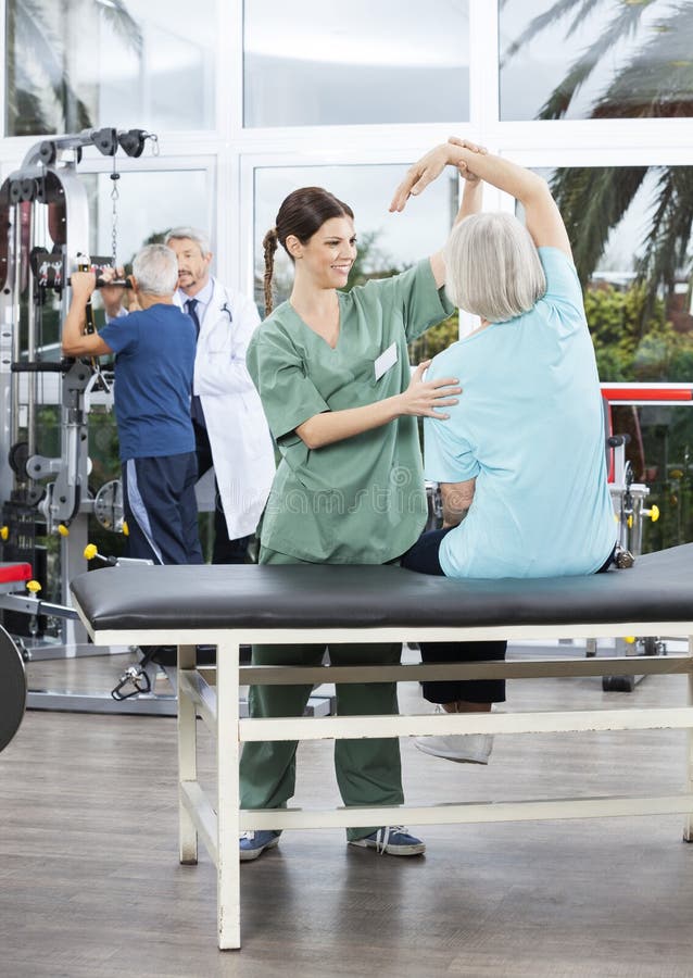 Infirmière Assisting Senior Woman dans l'exercice de bras au centre de réadaptation photographie stock libre de droits Infirmière Assisting Senior Woman dans l'exercice de bras au centre de réadaptation photographie stock libre de droits