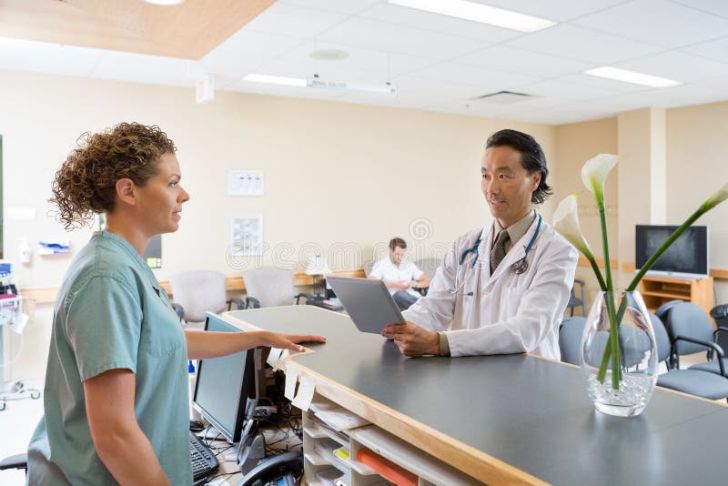 Infirmière And Doctor Conversing à la réception d'hôpital photos stock Infirmière And Doctor Conversing à la réception d'hôpital photos stock