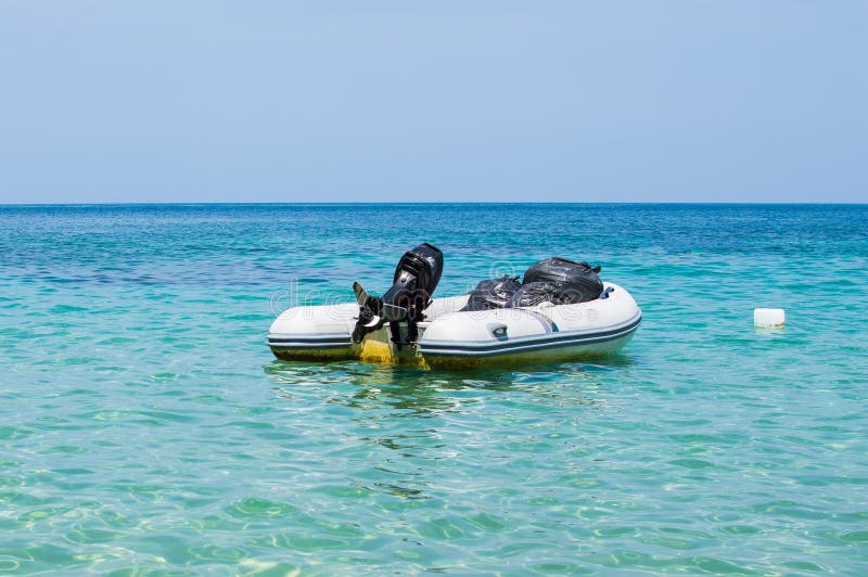 Inflatable Dinghy Boat with Outboard Motor Moored in Tropical Sea Stock