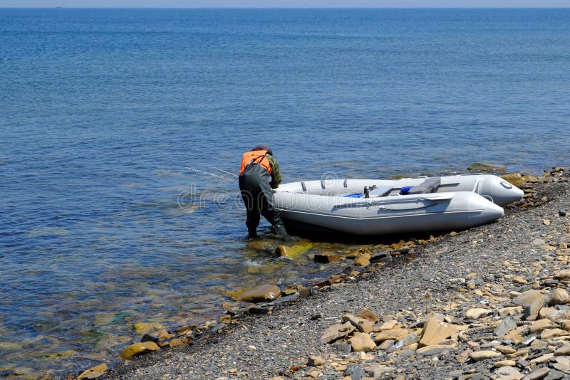 An Inflatable Rubber Fishing Boat on a Rocky Ocean Shore is