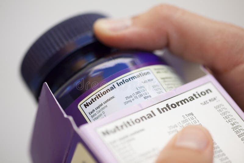 Human hand take out bottle with vitamin pills from the box for reading Nutritional information. Human hand take out bottle with vitamin pills from the box for reading Nutritional information.