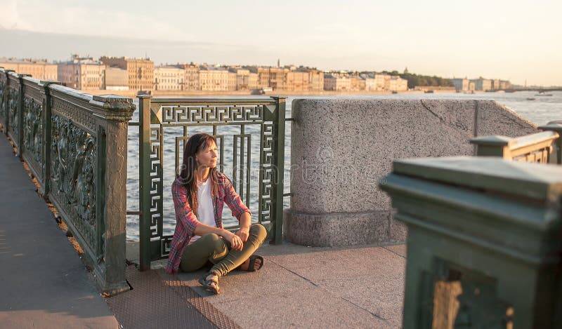 Informal girl sitting on the bridge in the morning, meditating, relaxing and dreaming. the concept of personal harmony and personal growth, peace of mind