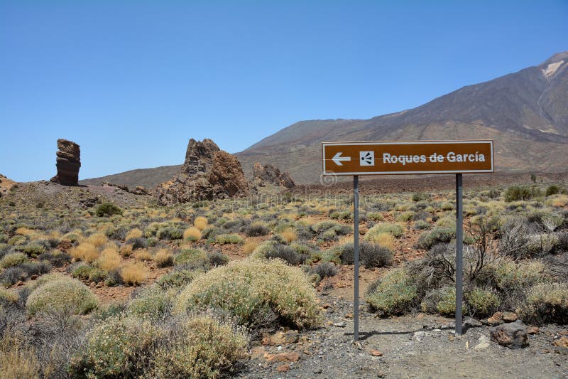 Information sign from the bizarrely shaped Roque Cinchado rock of volcanic rock in Teide National Park on the Canary Island of Tenerife, Spain. With views of Mount Teide and blue skies. Information sign from the bizarrely shaped Roque Cinchado rock of volcanic rock in Teide National Park on the Canary Island of Tenerife, Spain. With views of Mount Teide and blue skies