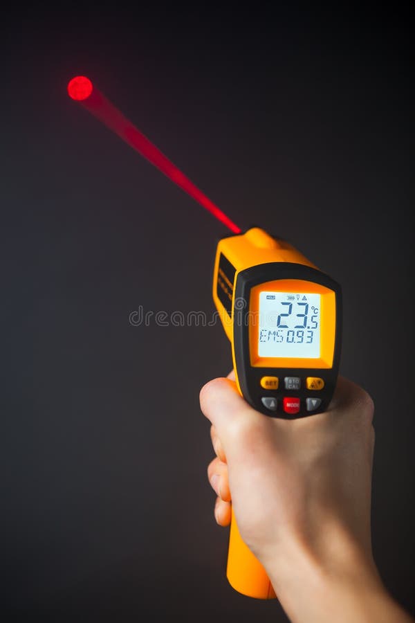 Infrared laser thermometer in hand, black background