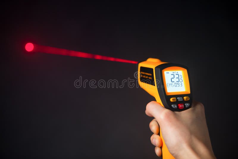 Infrared laser thermometer in hand, black background