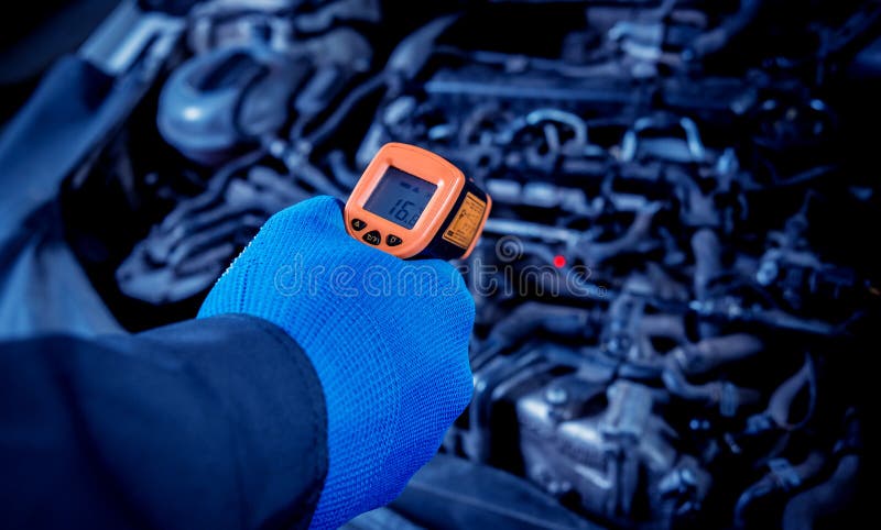 Infrared laser thermometer in hand. Motor temperature measurement in the car service