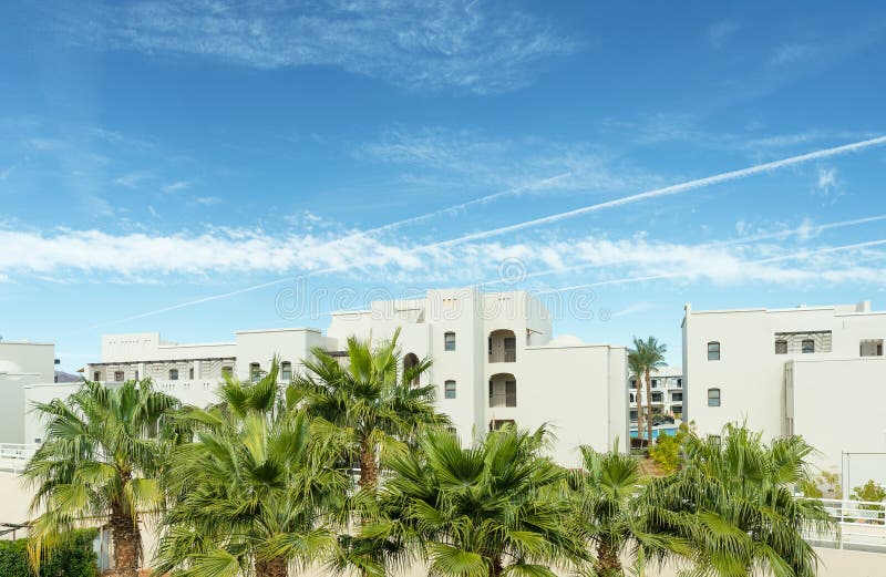 View at palm trees and a hotel foreside with blue sky and clods over it. Resort in Egypt. View at palm trees and a hotel foreside with blue sky and clods over it. Resort in Egypt