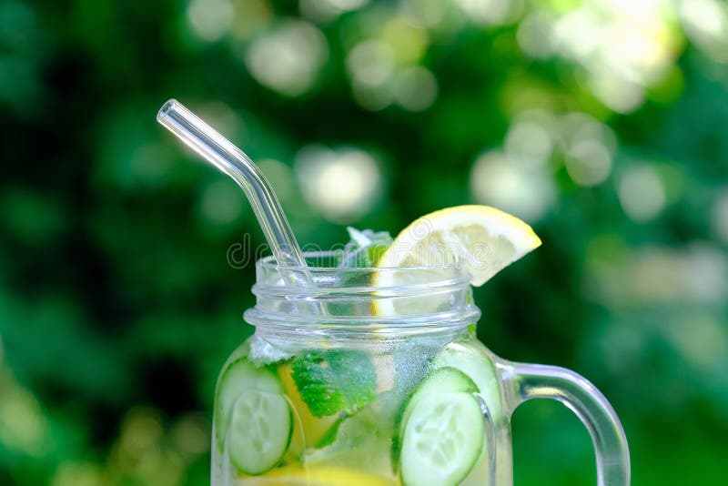 Infused detox water with cucumber, lime and mint in glass jar with drinking straw. Summer cocktail, cool fresh lemonade. Close-up view