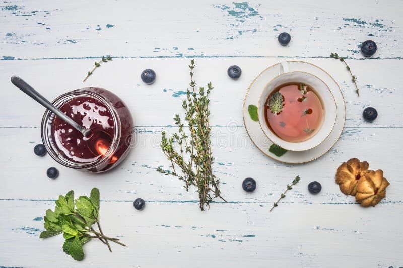 Infusión de hierbas caliente con la menta, el atasco de la alcaravea de una rosa, y las galletas, en un fondo rústico de madera, fotos de archivo libres de regalías Infusión de hierbas caliente con la menta, el atasco de la alcaravea de una rosa, y las galletas, en un fondo rústico de madera, fotos de archivo libres de regalías